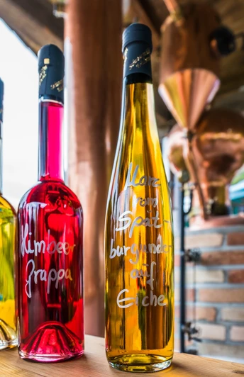 Beschriftete Schnapsflaschen mit rotem und gelbem Inhalt auf einem Tisch