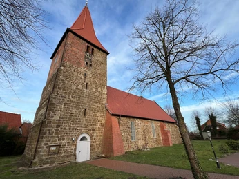 St. Bartholomäus Kirche Balge Eine historische Kirche mit einem hohen Glockenturm aus Backstein im Grünen von Balge.