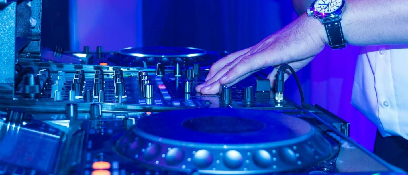 Nightlife Club Aachen Ein DJ legt im Nachtclub Platten auf, während bunte Lichter die Mischpulte beleuchten.