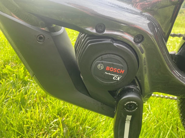 Nahaufnahme eines schwarzen Bosch Performance Line CX E-Bike-Motors auf grünem Gras.