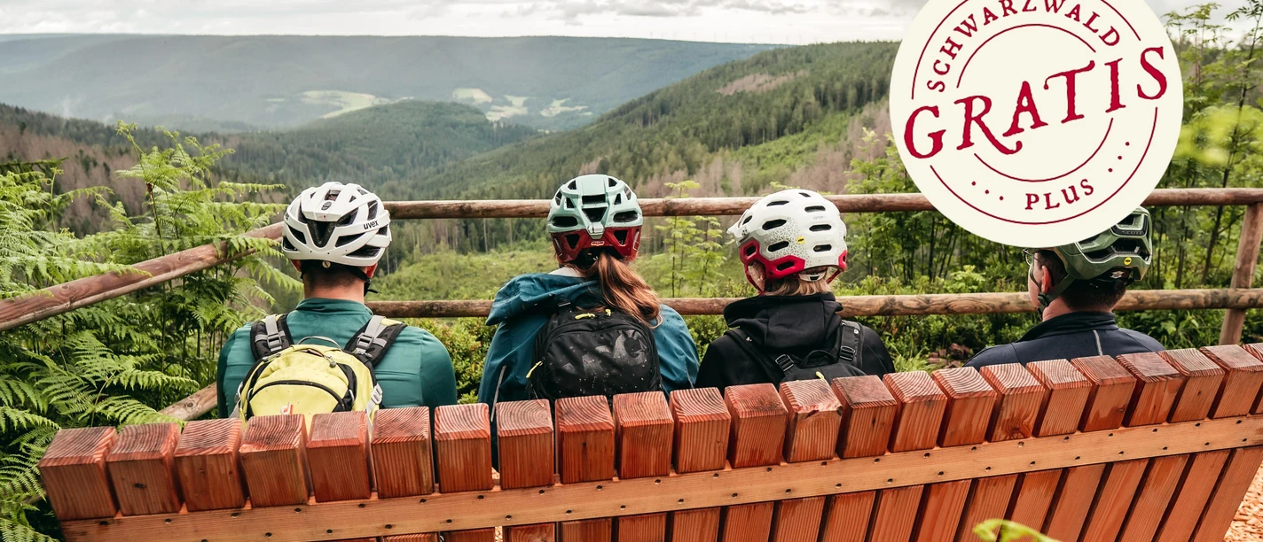 Mountainbiker sitzen auf einer Bank mit Ausblick