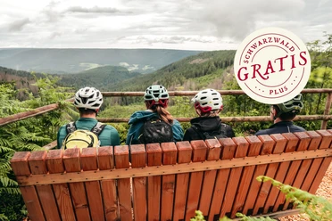 Mountainbiker sitzen auf einer Bank mit Ausblick