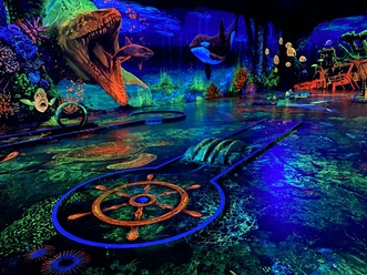 Schwarzlichtgolf.jpeg Faszinierendes Schwarzlicht-Minigolf mit lebhaften Unterwasserszenen und leuchtenden Farben.