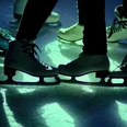 Eislaufdisco in Aachen Nahaufnahme von mehreren Schlittschuhen auf beleuchteter Eisfläche.