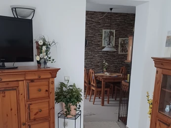 Wohnraum in der Gästewohnung Werkerwald in Heiligenhaus Ein einladender Wohnbereich mit Holzmöbeln, floralen Akzenten und offener Verbindung zum Essbereich.