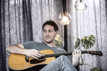 buesum-Gerrit Hoss.jpg Ein Mann sitzt und spielt eine Gitarre.