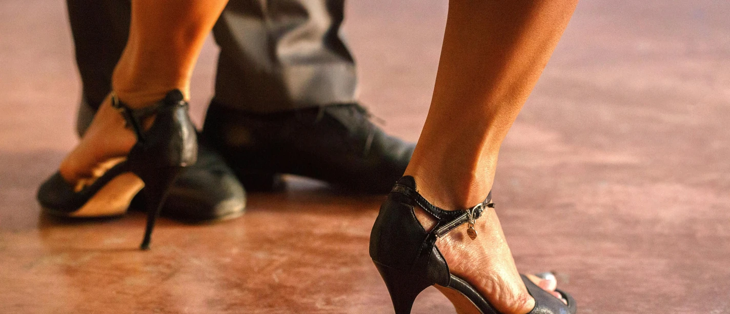 Salsa im LaL (c) pexels.jpg Schwarze Absatzschuhe und polierte Herrenschuhe tanzen eng beieinander auf einem Holzboden.