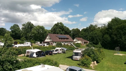EurocampLienen20220611-E-Krützmann.jpg Ein Campingplatz mit Wohnmobilen und Zelten in grüner Umgebung, von Bäumen umgeben und sonnig.