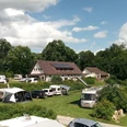 EurocampLienen20220611-E-Krützmann.jpg Ein Campingplatz mit Wohnmobilen und Zelten in grüner Umgebung, von Bäumen umgeben und sonnig.
