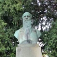 Herford-Jahn_Denkmal_Pro Herford.jpg Büste von Friedrich Ludwig Jahn auf einem Sockel, umgeben von dichten, grünen Nadelbäumen.