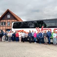 FStadtrundfahrtStadtführerVHS_.jpg Eine Gruppe Touristen steht vor einem großen Reisebus und einem traditionellen Fachwerkhaus.
