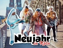 Vier verkleidete Personen feiern auf einer Kölner Brücke den Jahreswechsel, der Dom im Hintergrund.