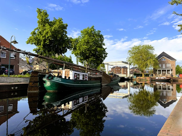 Plattbodenschiff Ebenhaezer am Untenende, Gemeinde Rhaudereféhn, IMG_8194.JPG Grünes Segelschiff liegt an einem ruhigen Kanal mit Bäumen und Häusern im Hintergrund