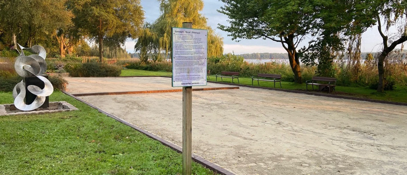 Bouleplatz-Bad-Zwischenahn.jpg Ein Bouleplatz in Bad Zwischenahn, umrahmt von schattigen Bäumen, lädt zum Spielen und Verweilen ein.