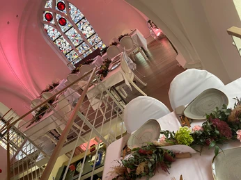 IMG_0970 2.jpeg gedeckte Tische mit Blumendeko auf der Empore der Eventkapelle mit großem Buntglasfenster im HintergrundTables laid with floral decorations in the gallery of the event chapel with a large stained glass window in the background