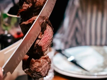 Rodizio Minden II.JPG Das Bild zeigt einen Fleischspieß, der frisch vom Kellner am Tisch abgeschnitten wird.