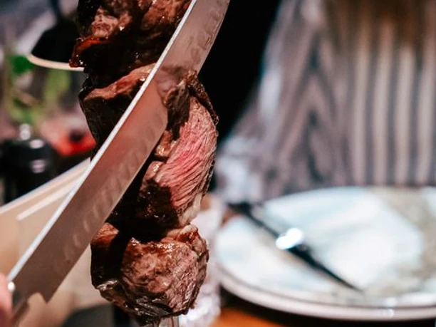 Rodizio Minden II.JPG Das Bild zeigt einen Fleischspieß, der frisch vom Kellner am Tisch abgeschnitten wird.