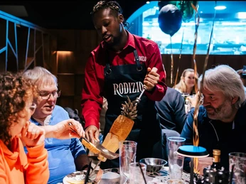 Rodizio Minden III.JPG Das Bild zeigt einen Kellner, der einem Gast ein Stück Ananas vom Spieß direkt am Tisch auf den Teller abschneidet