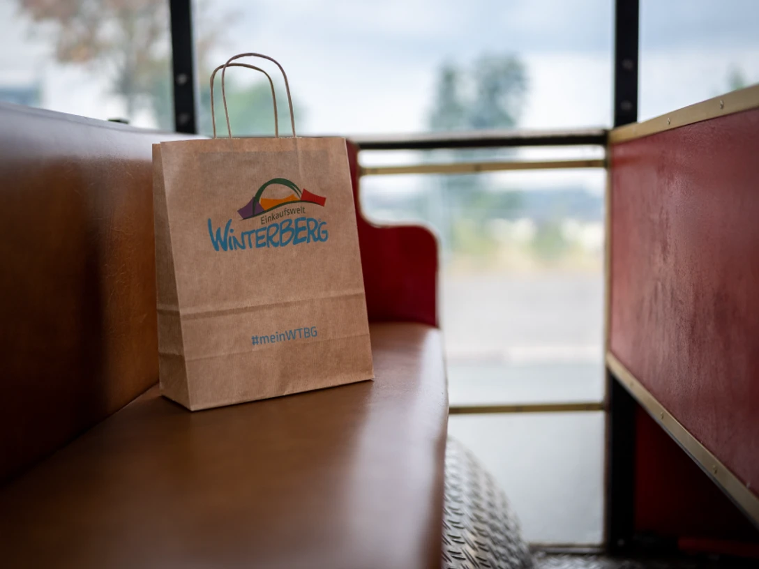 Eine Winterberger Einkaufstüte aus Papier auf einer roten Sitzbank. Dieses Bild dient als Symbolbild für Einkaufsmöglichkeiten.