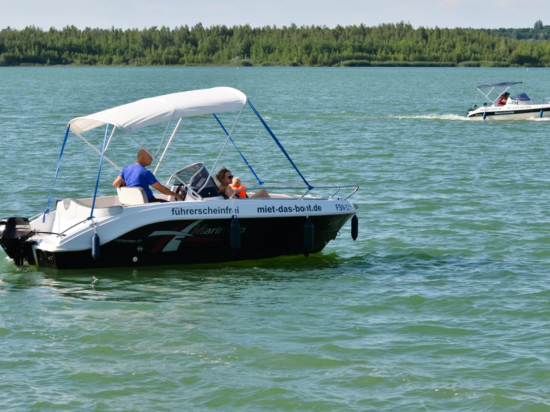 Führerscheinfreier Bootsverleih Störmthaler Hafen.jpg Das Bild zeigt zwei fahrende Boote auf dem Störmthaler See, worauf sich mehrere Personen befinden, ab. Auffällig ist das traumhafte Wetter, dass sich durch die klare Sicht, wolkenlosen Himmel und stralenden Sonnenschein auszeichnet. Die Boote sind mit der Aufschrift "führerscheinfrei" und "miet-das-boot.de" versehen und können am Störmthaler Hafen ausgeliehen werden.The picture shows two moving boats on Lake Störmthal with several people on board. What is striking is the fantastic weather, which is characterized by clear visibility, cloudless skies and bright sunshine. The boats are marked "no license required" and "miet-das-boot.de" and can be hired at Störmthal harbour.Na obrázku jsou dva čluny plující po jezeře Störmthal s několika lidmi na palubě. Nápadné je fantastické počasí, které se vyznačuje jasnou viditelností, oblohou bez mráčku a jasným slunečním svitem. Čluny jsou označeny nápisy "bez licence" a "miet-das-boot.de" a lze si je pronajmout v přístavu Störmthal.Zdjęcie przedstawia dwie łodzie podróżujące po jeziorze Störmthal z kilkoma osobami na pokładzie. Uderzająca jest fantastyczna pogoda, charakteryzująca się dobrą widocznością, bezchmurnym niebem i jasnym słońcem. Łodzie są oznaczone jako "licence-free" i "miet-das-boot.de" i można je wynająć w porcie Störmthal.Op de foto zie je twee boten varen op het Störmthal meer met verschillende mensen aan boord. Wat opvalt is het fantastische weer, gekenmerkt door helder zicht, een wolkenloze hemel en stralende zon. De boten hebben het label "vaarbewijsvrij" en "miet-das-boot.de" en kunnen worden gehuurd in de haven van Störmthal.L'immagine mostra due barche che viaggiano sul lago di Störmthal con diverse persone a bordo. Ciò che colpisce è il tempo fantastico, caratterizzato da visibilità chiara, cielo senza nuvole e sole splendente. Le imbarcazioni sono contrassegnate dalle diciture "senza patente" e "miet-das-boot.de" e possono essere noleggiate al porto di Störmthal.