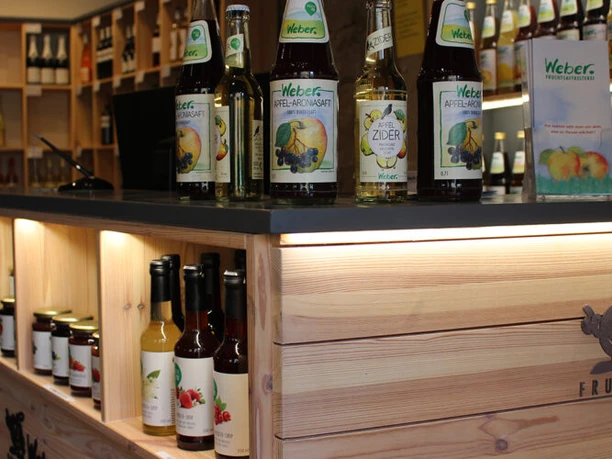 Saftladen Verkaufsraum mit hölzerner Theke, auf der diverse Fruchtsäfte und Produkte ausgestellt sind.