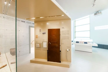 Bright exhibition room, a brown cell door in the center