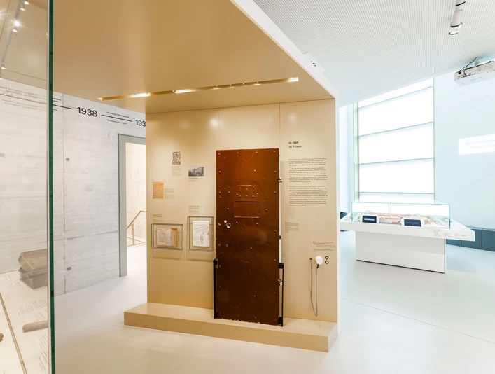 Heller Ausstellungsraum, im Zentrum eine braune ZellentürBright exhibition room, a brown cell door in the centerLyst udstillingsrum, en brun celledør i midtenLichte tentoonstellingsruimte, een bruine celdeur in het midden