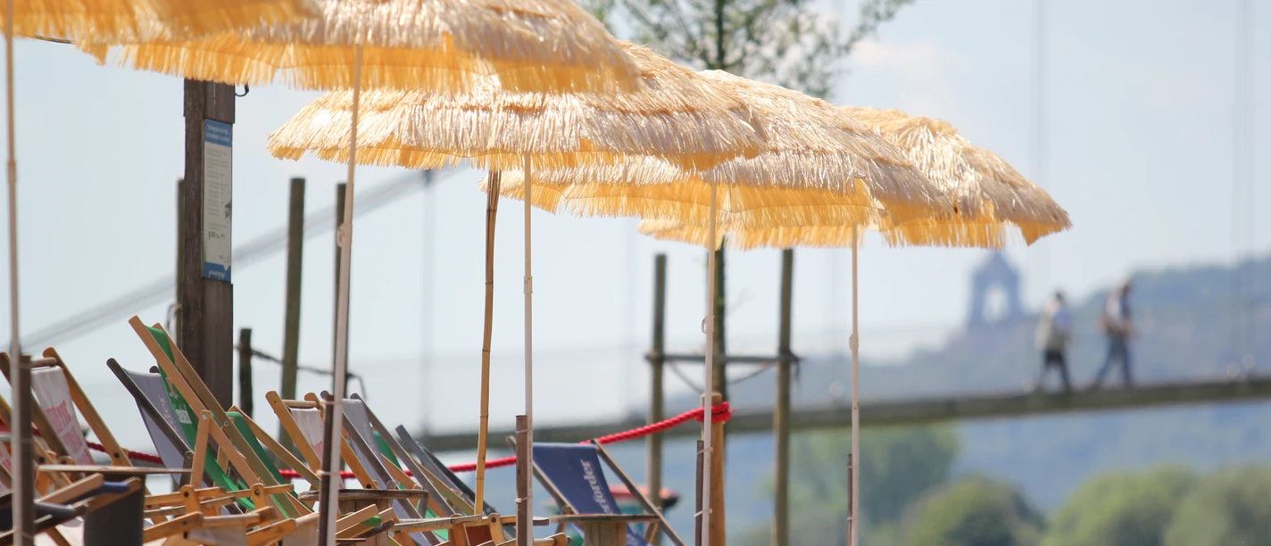 Minden - Weserstrand.JPG Das Bild zeigt den Mindener Weserstrand mit Strandliege und Sonnenschirm.