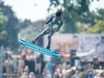 EAT PLAY LOVE Festival A young person in action wakeboarding, jumping dynamically over the water, spraying spray.