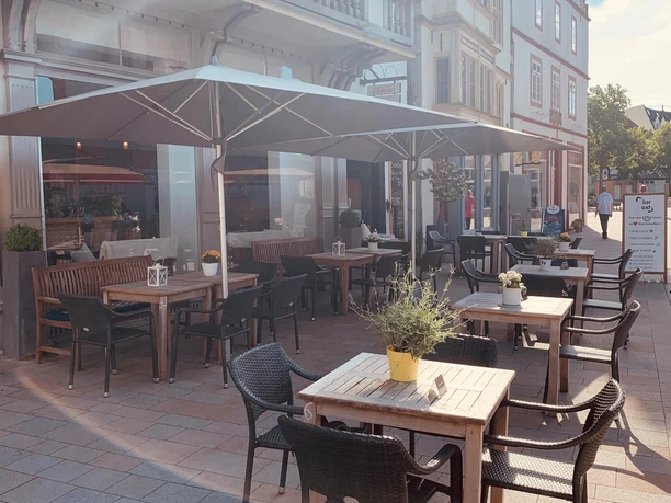 Außenterrasse des Bistro KlarText mit Sonnenschirmen vor historischen Fassaden