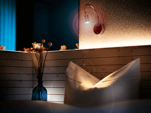 Zimmer im Gästehaus FETTE HENNE in Erkrath Kissen und Lampe in einem stilvoll beleuchteten Gästezimmer mit Holzelementen, dezente Wandtapete.