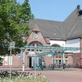 Historischer Haupteingang des Herforder Hauptbahnhofs mit Fahrradständern und angrenzendem Café.