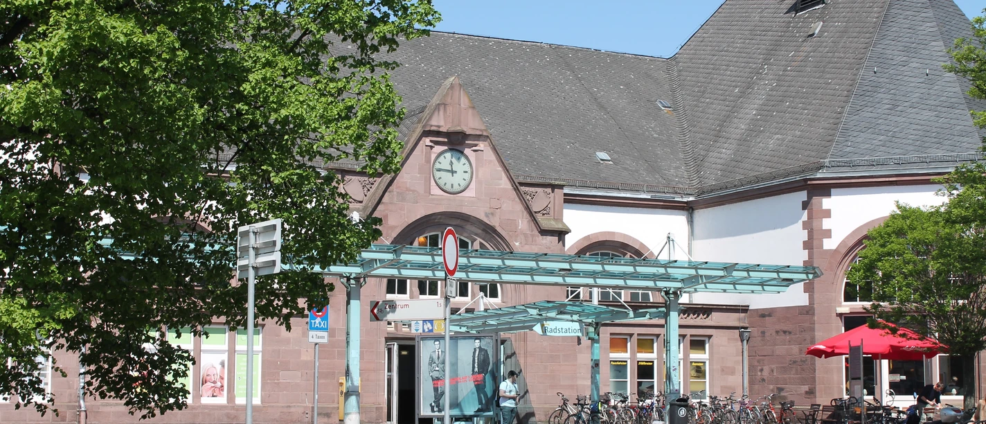 Historischer Haupteingang des Herforder Hauptbahnhofs mit Fahrradständern und angrenzendem Café.