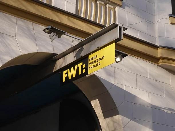 Freies Werkstatt Theater Fotografie des Eingangs zum Freien Werkstatt Theater Köln mit gelbem Schild überm Bogen.