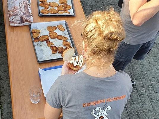 Kolpingjugend Eine Gruppe bereitet Schnitzel auf Tabletts vor; eine Frau trägt ein T-Shirt der Kolpingjugend.