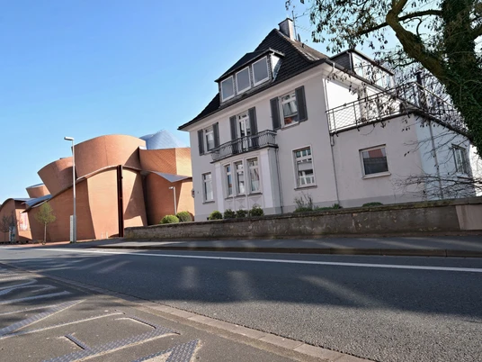 Ahlers Pro Arte_240803_SAPA_MW.jpg Straßenansicht eines zweistöckigen Hauses mit Schieferdach, daneben ein modernes Backsteingebäude.