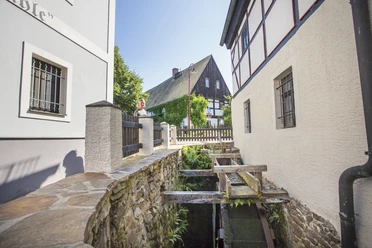 Wassermühle in Höfgen Fouad Vollmer Werbeagentur.jpg Das Bild zeigt die Wassermühle des Dorf Höfgen, die von Fachwerkhäusern und dem historischen Gasthaus eingerahmt wird