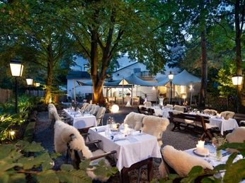 Biergarten im Gästehaus FETTE HENNE in Erkrath Stimmungsvolle Atmosphäre im Biergarten mit beleuchteten Tischen, Kerzen und umringt von Bäumen.