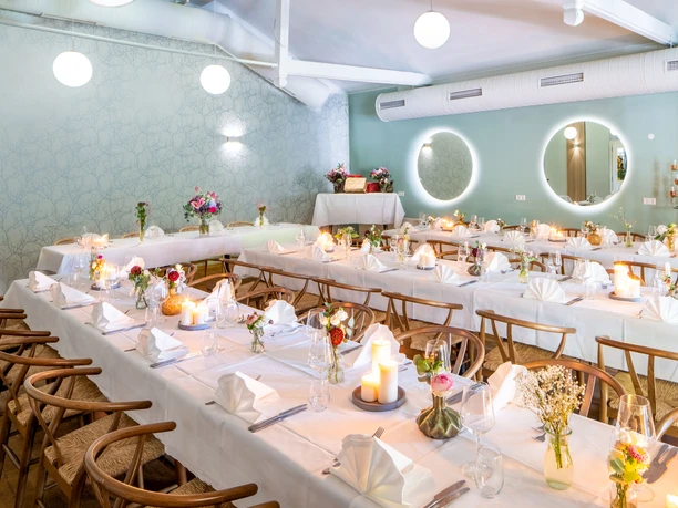 Veranstaltungsraum im Gästehaus FETTE HENNE, Erkrath Eleganter Veranstaltungsraum mit gedeckten Tischen, stimmungsvoller Beleuchtung und frischen Blumen.