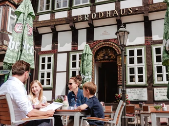 Een gezin met twee kinderen zit aan een tafel voor het Brodhaus.
