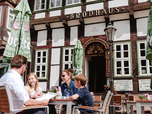 Een gezin met twee kinderen zit aan een tafel voor het Brodhaus.