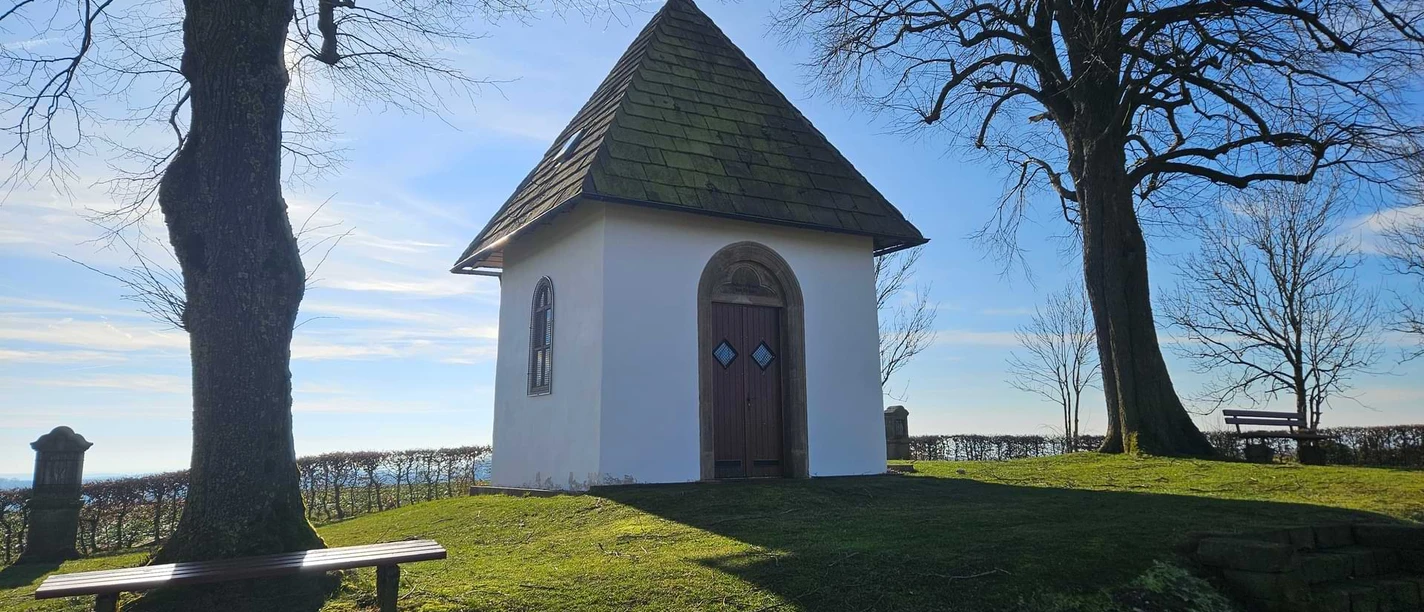 Bad-Driburg-Pömbsen-Bad-Driburger-Touristik-GmbH-03-kom.jpg Die Kluskapelle mit zwei Bäumen und Sitzgelegenheiten in Pömbsen.