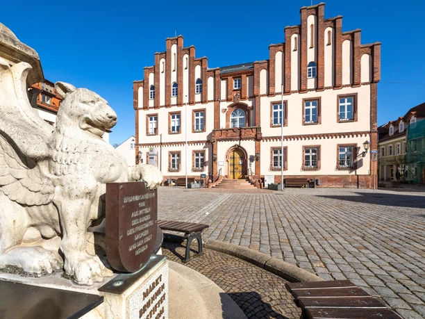 Marktplatz und Rathaus von Mügeln Das Bild zeigt den Marktplatz von Mügeln mit dem Brunnen und den histroischen Staturen sowie den Marktplatz der Stadt.