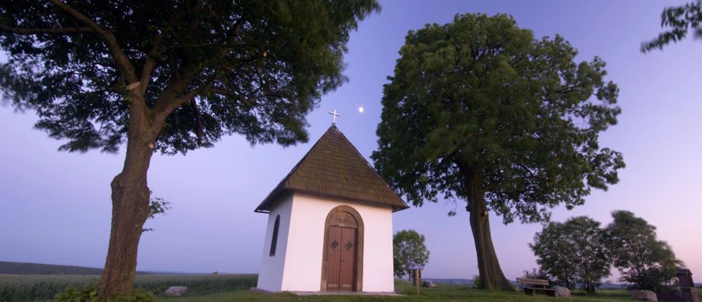 Kluskapelle von außen bei Dämmerung in Pömbsen.