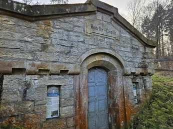 Bad-Driburg-Herste-Koerfer-Quelle-Bad-Driburger-Touristik-GmbH-2_kom.jpeg Im Vordergrund das Schild der Koerfer Quelle und im Hintergrund das Haus, in Herste.
