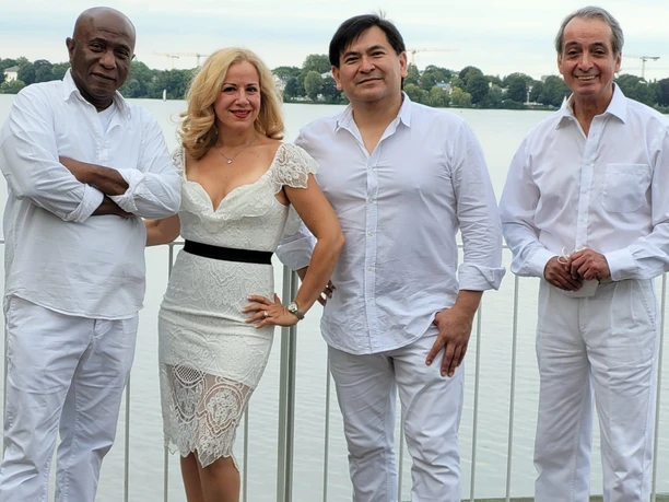 Seebühne Sal Y Mango Een groep van vier mensen in witte outfits poseert glimlachend voor een kalm meer.