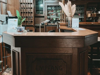 Rezeption des Herford-Gästehauses Janzen mit dunkler Holztheke, Dekor und informativen Aufstellern.