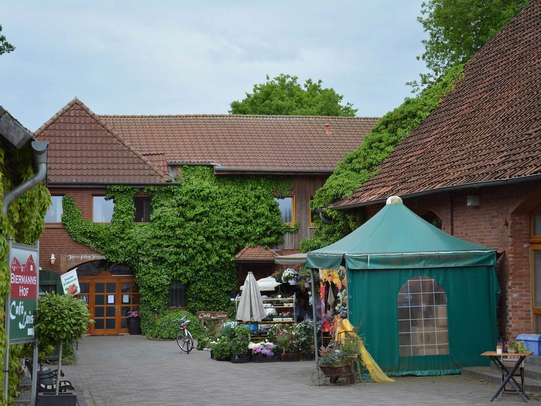 eilvese Ein Hof mit Ziegelgebäuden und grünem Bewuchs, ein Verkaufsstand mit Pflanzen und Dekorationen.