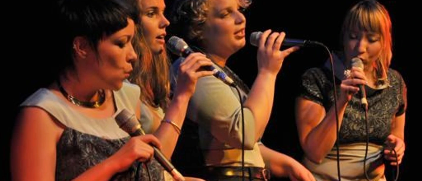 Kultur Gulfhof Freepsum: niniwe Vier Sängerinnen der Gruppe niniwe bei einem Live-Auftritt auf der Bühne mit Mikrofonen.