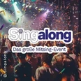 Bunte Bühne mit singendem Publikum und Konfetti bei einer lebhaften Eventatmosphäre.